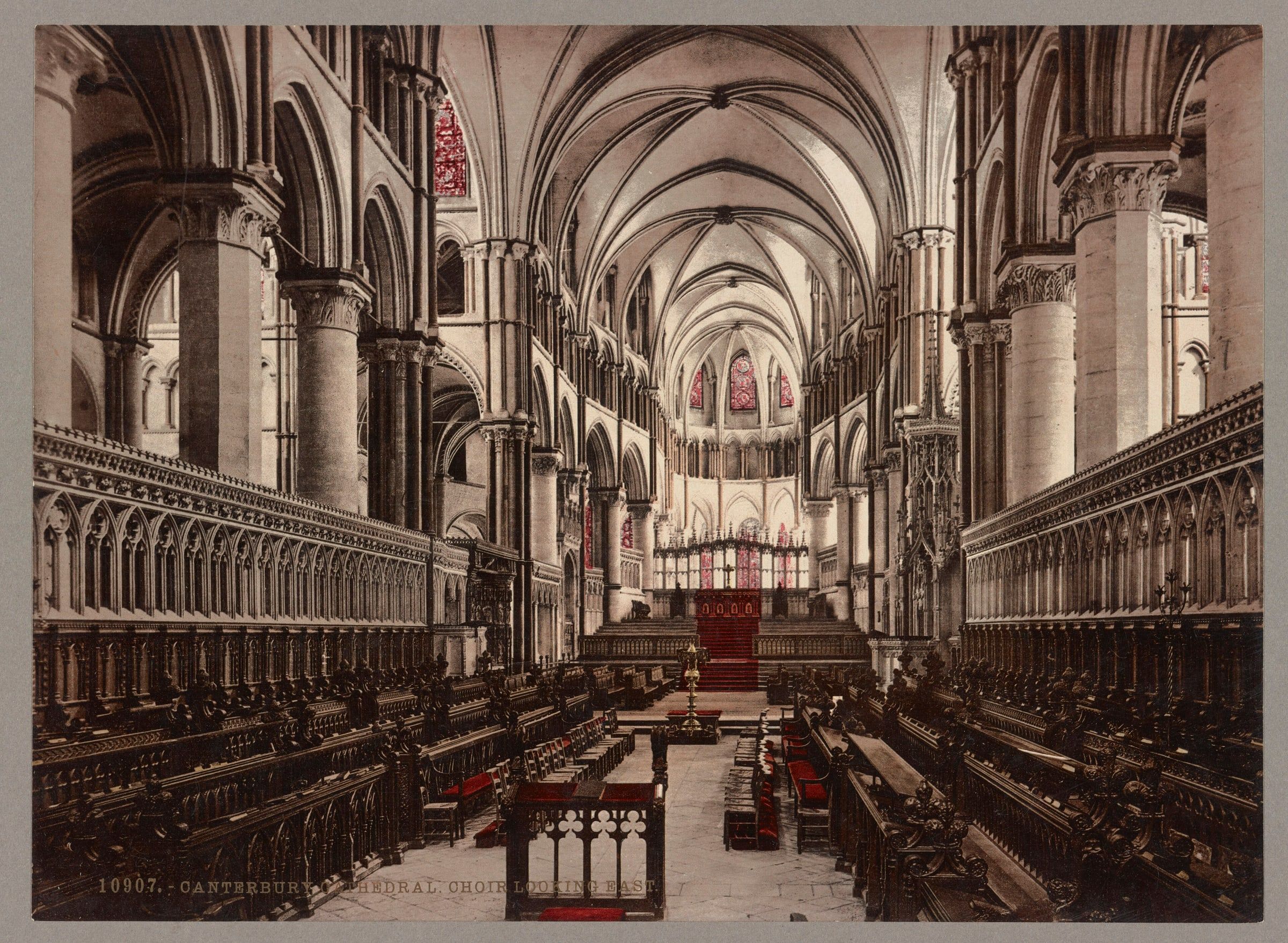 A hand-coloured photochrom of Canterbury Cathedral’s choir, looking east past carved stalls towards the high altar.