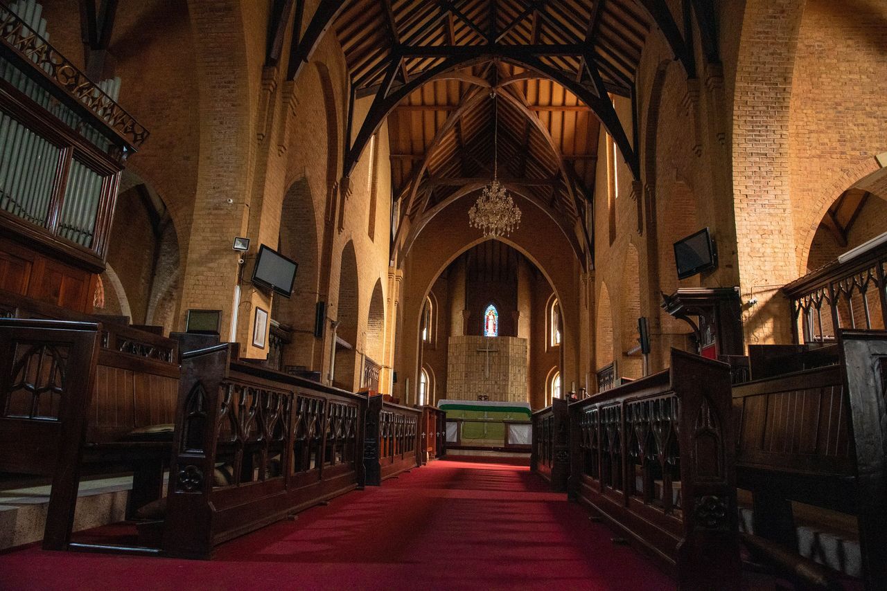 The nave of Namirembe Cathedral in Kampala: a red carpet runs between dark wooden choir stalls towards the altar, under a high timber roof.